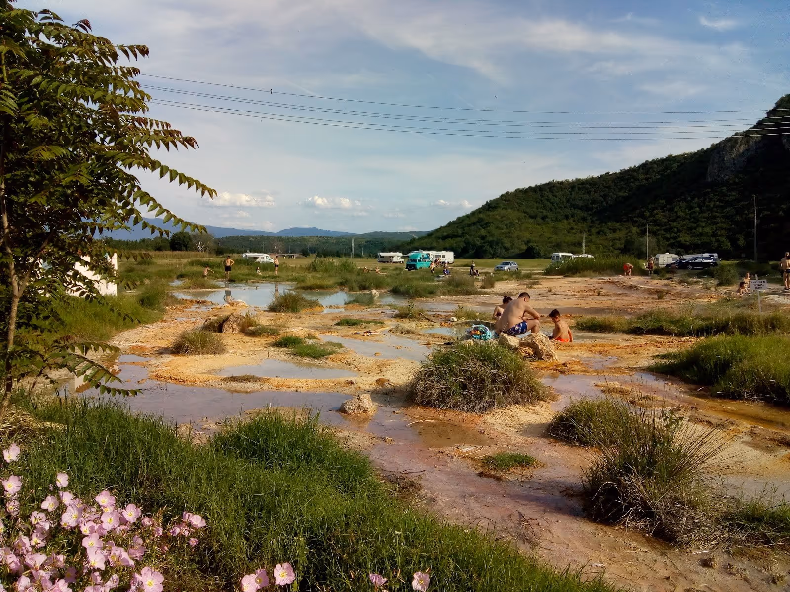 Visitors enjoying multiple natural mineral pools with clear water and grassy patches at Rupite Thermal Springs near Petrich Bulgaria.