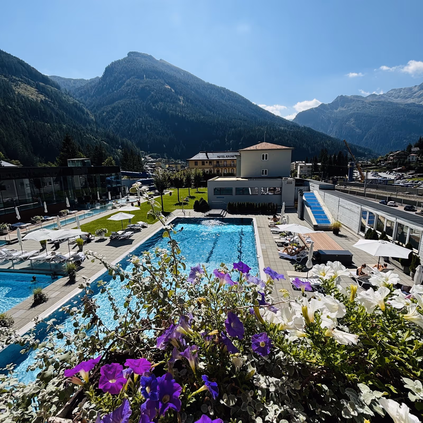 Outdoor hot spring pool at Felsentherme Bad Gastein with clear water, lounge chairs, umbrellas, and mountains in Bad Gastein, Austria.
