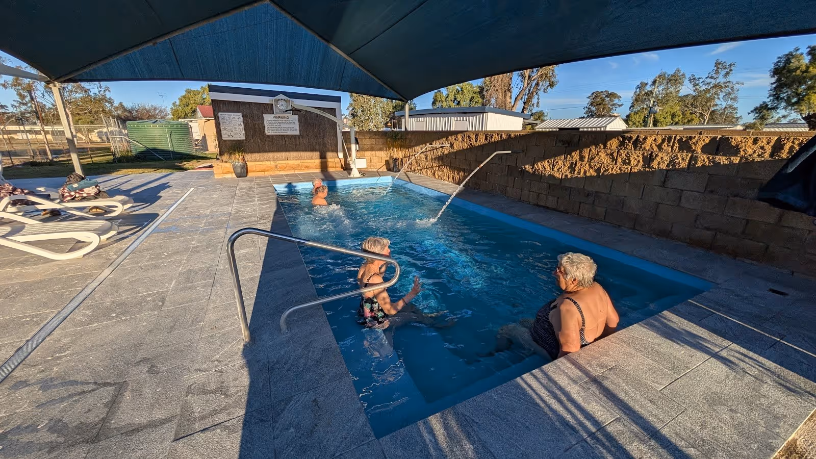 Outdoor mineral pool at Boomi Artesian Spa Pools in Boomi New South Wales Australia with people enjoying the water under shade.