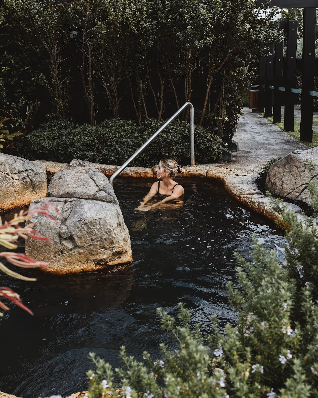 Natural stone soaking pool surrounded by green plants at Deep Blue Hot Springs near Warrnambool on the Great Ocean Road in Australia.