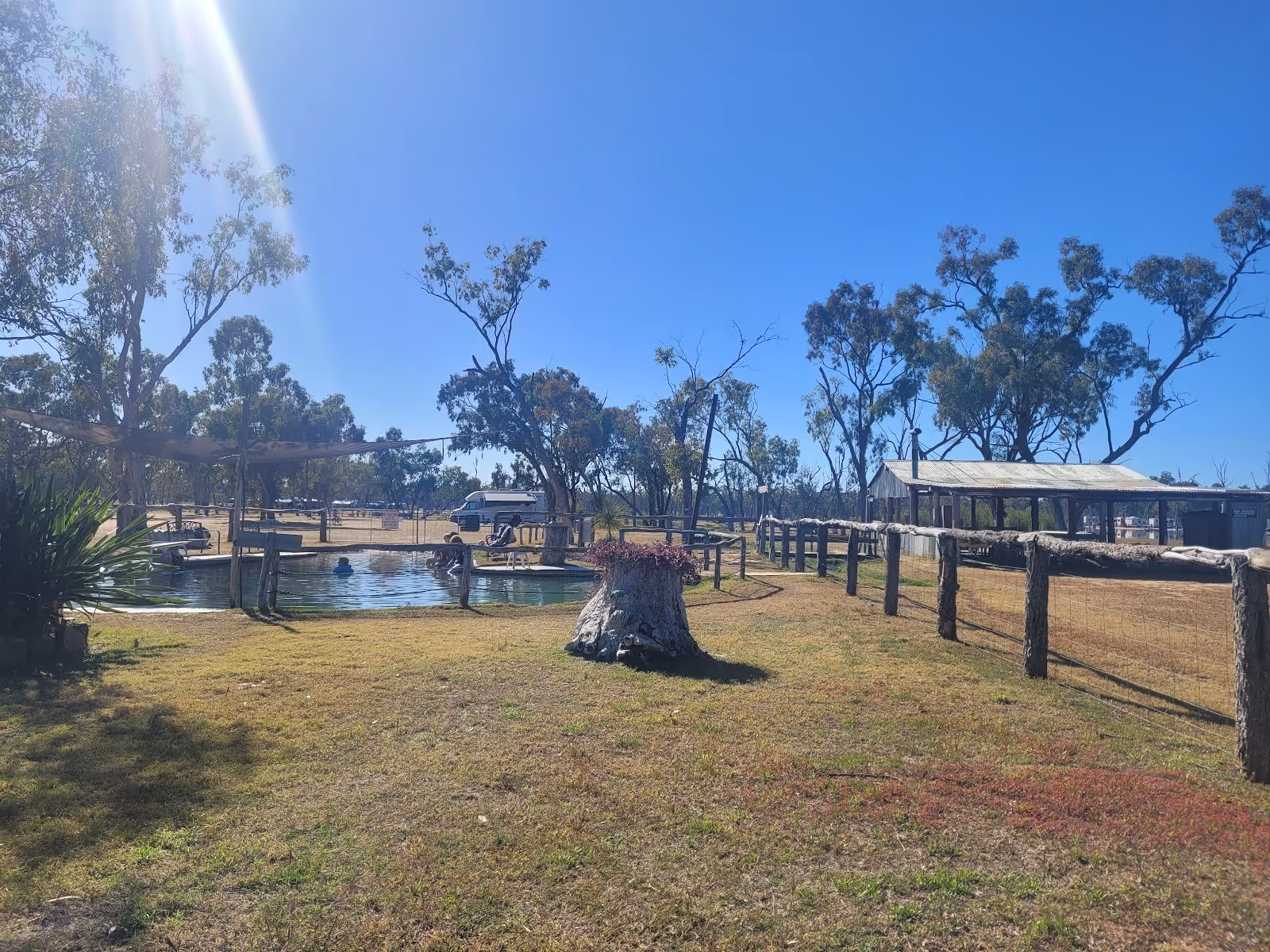A few people soak in a round thermal pool at Lara Wetlands thermal pool near Barcaldine area Queensland Australia on a sunny day.