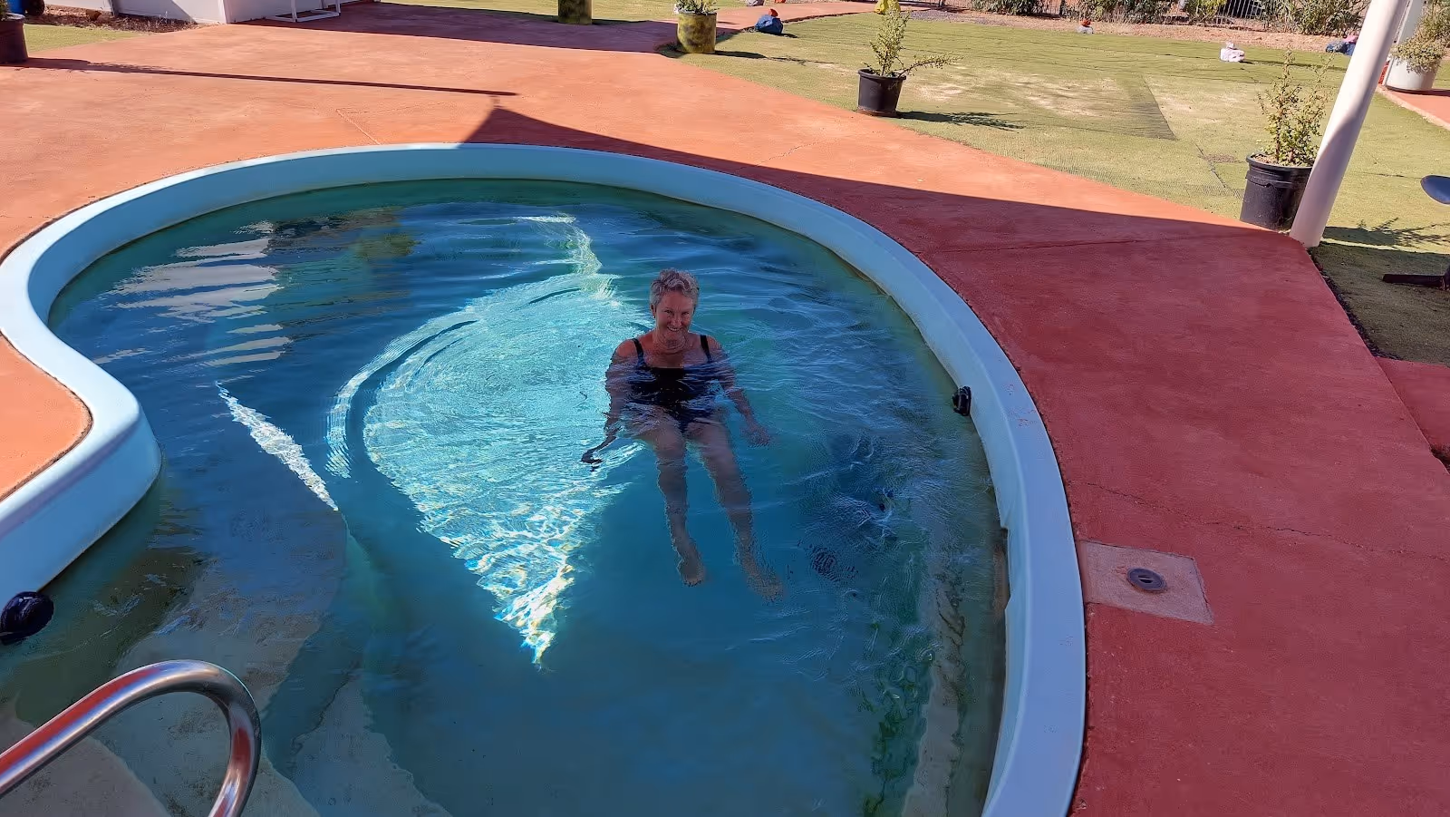 A woman sitting relaxed in a round blue hot spring pool at Yowah Artesian Pools in Yowah Queensland Australia.