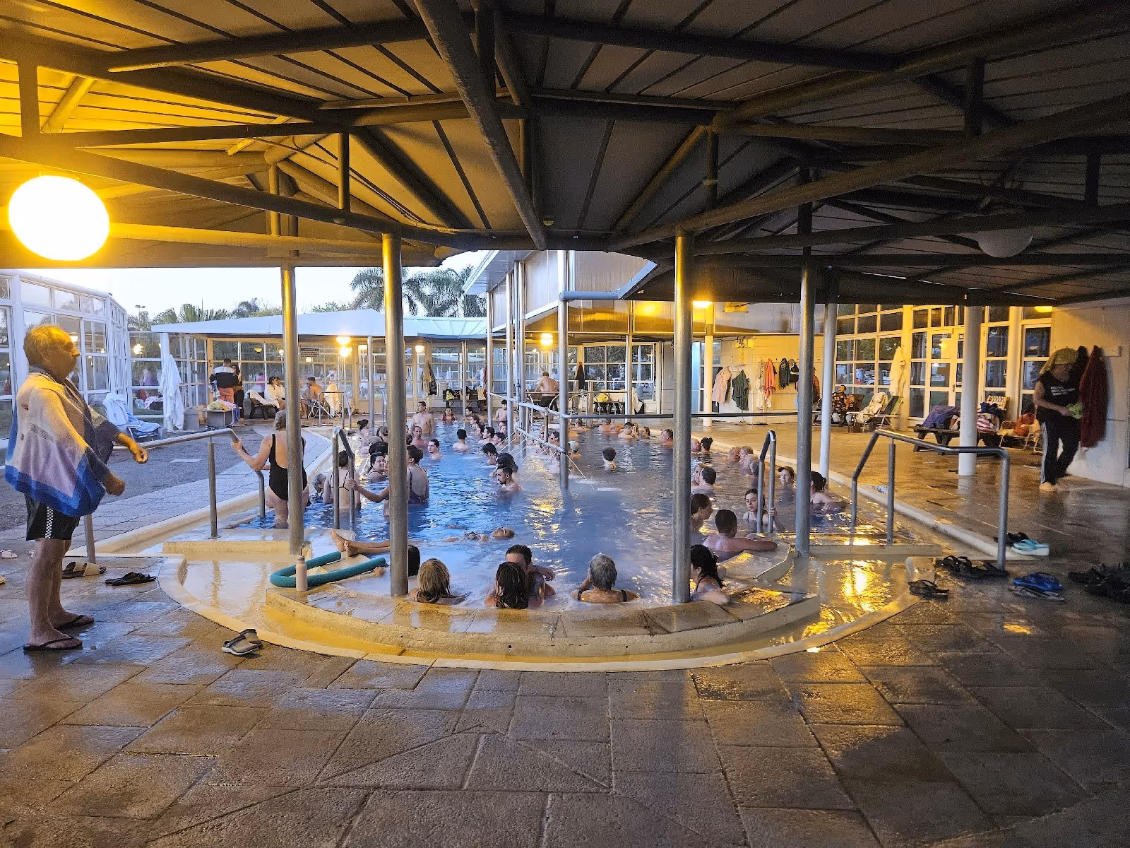 Indoor hot spring pool with many people soaking under a roof structure at Termas Villa Elisa near Villa Elisa, Argentina.