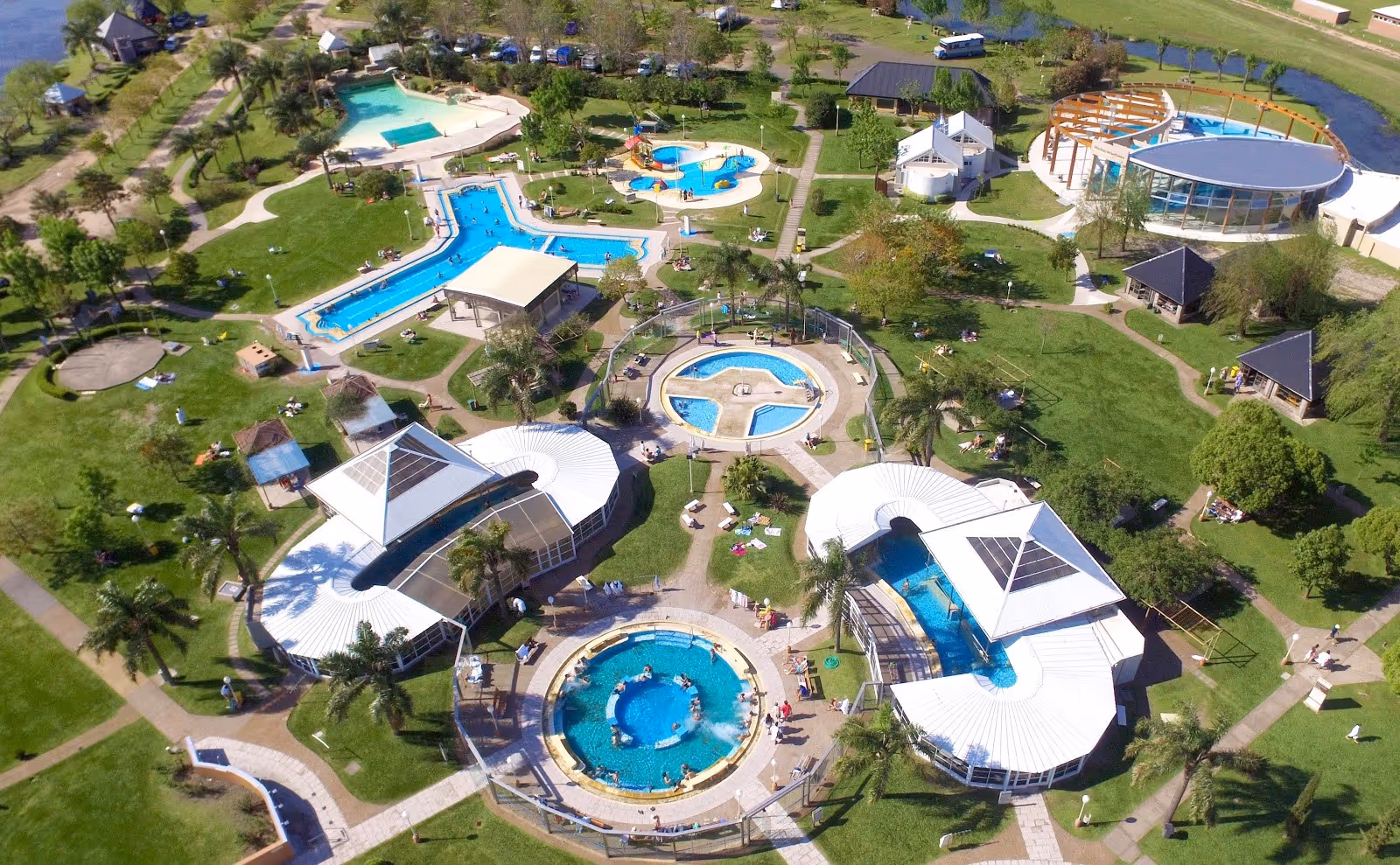 Aerial view of Termas Villa Elisa resort showing multiple pools, green lawns, and walking paths near Villa Elisa, Argentina.