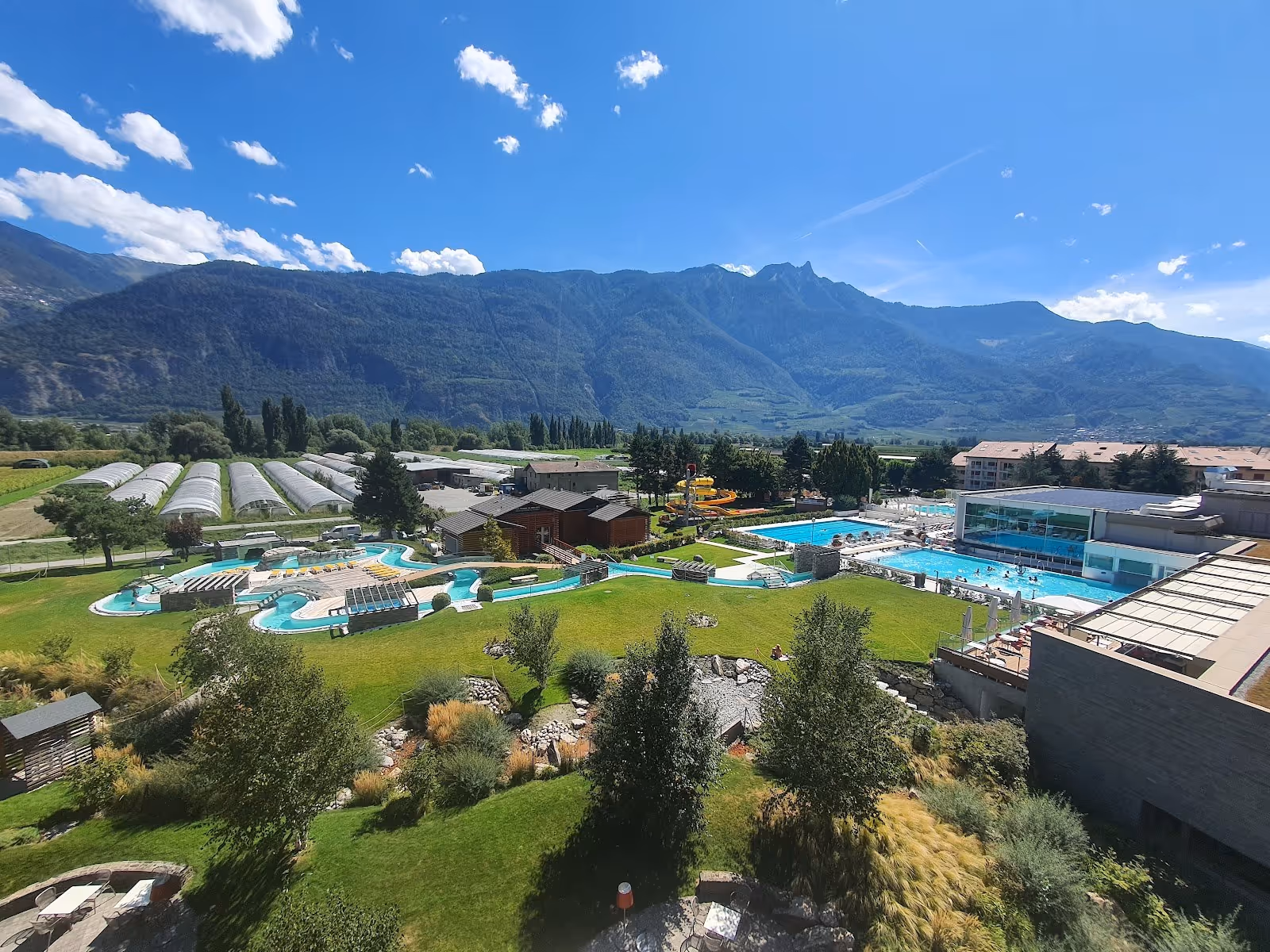 Outdoor spa pools with crystal clear water at Bains de Saillon surrounded by green grass and mountains near Martigny Switzerland.