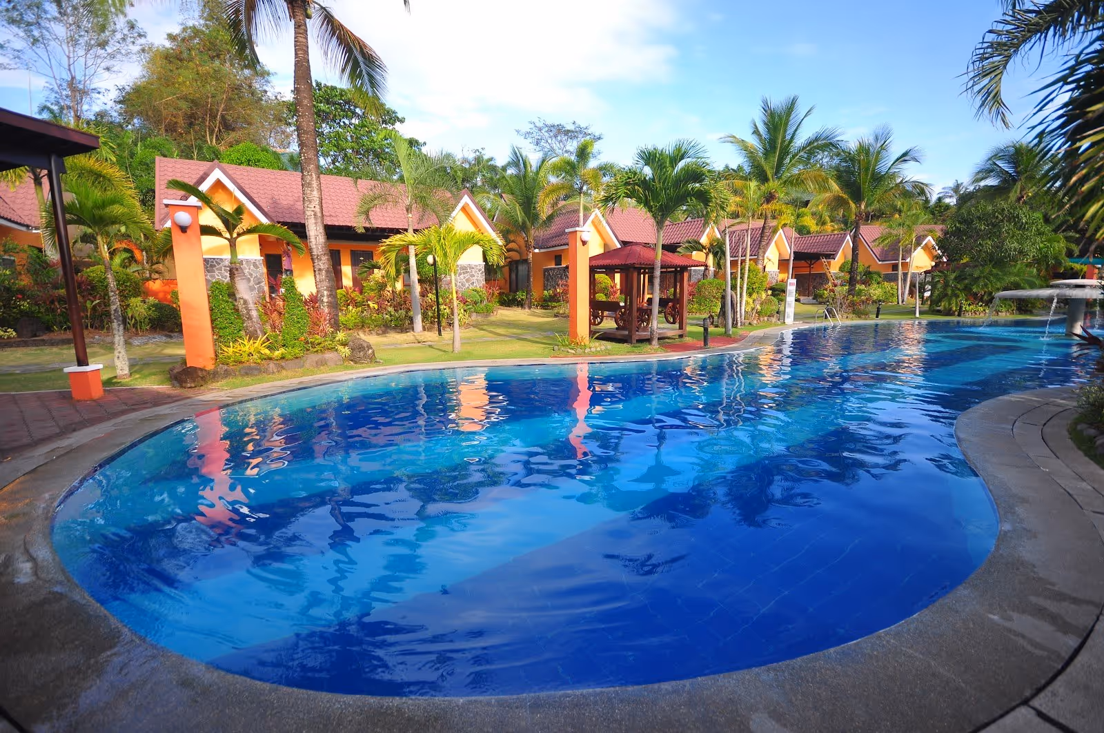 Large outdoor pool with palm trees and small gazebo nearby at 88 Hot Spring Resort, framed by neatly trimmed gardens in Calamba City Philip.