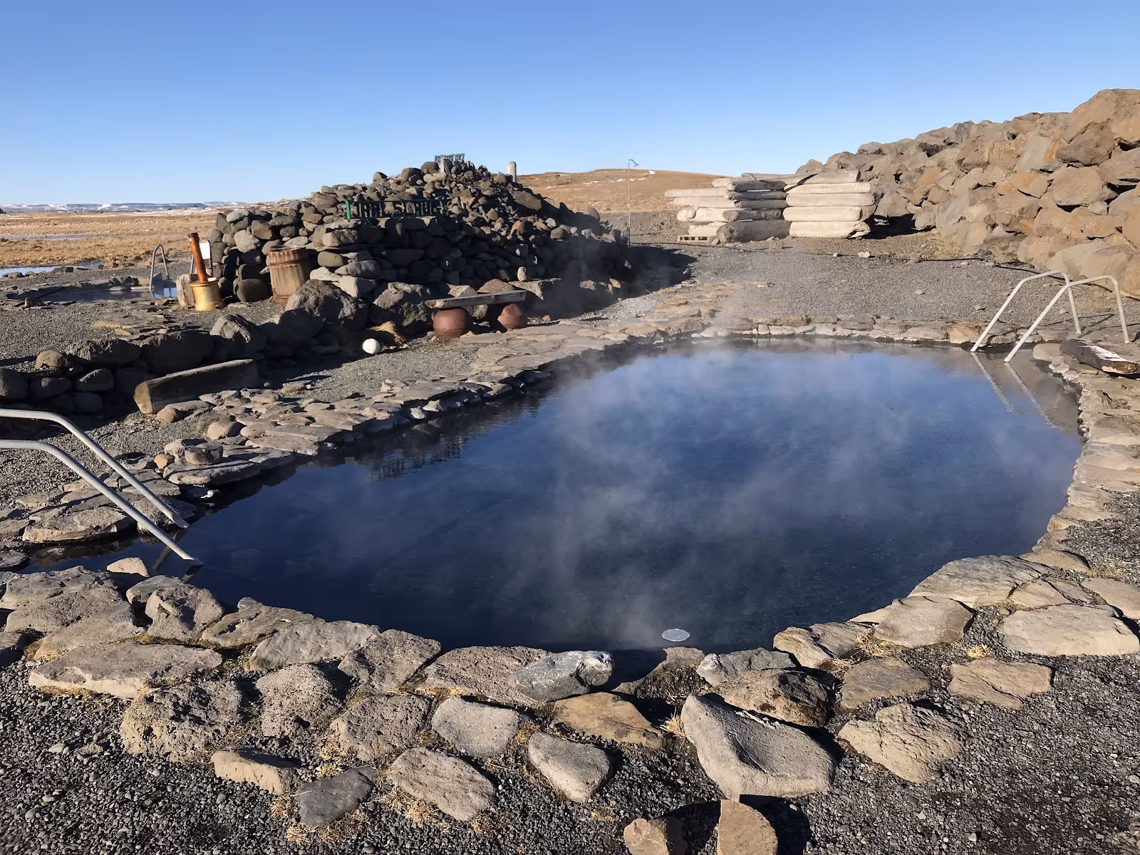 Steaming outdoor hot spring pool surrounded by stone walls at Grettislaug Hot Springs near Saudarkrokur Iceland.