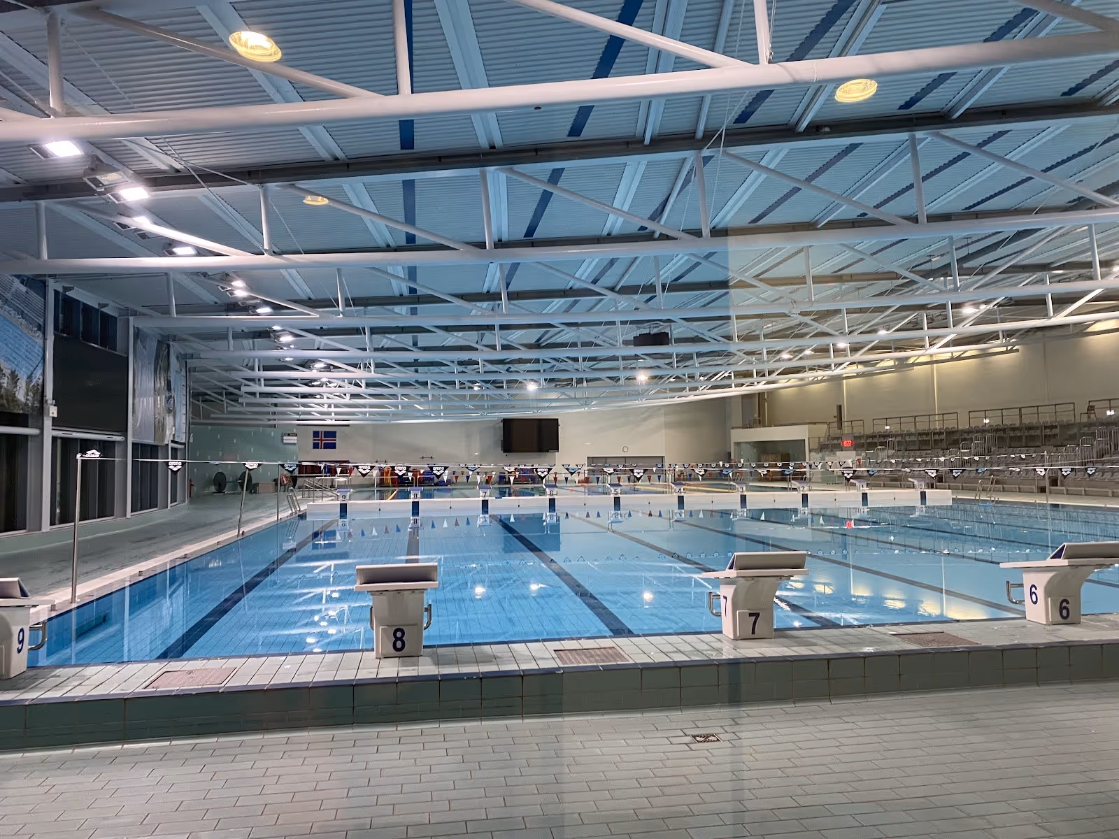 Indoor mineral pool area at Laugardalslaug with clear water, swimming lanes, and angled roof lights in Reykjavik Iceland.