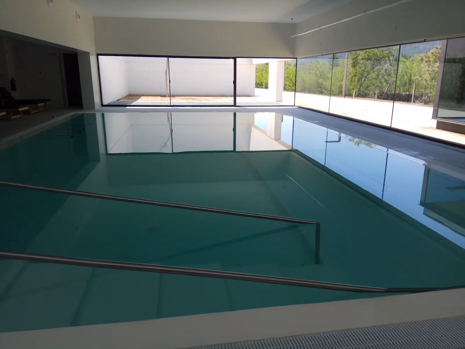 Indoor soaking pool with clear water and metal handrails at Balneario Pedagogico de Vidago in Vidago, Portugal.