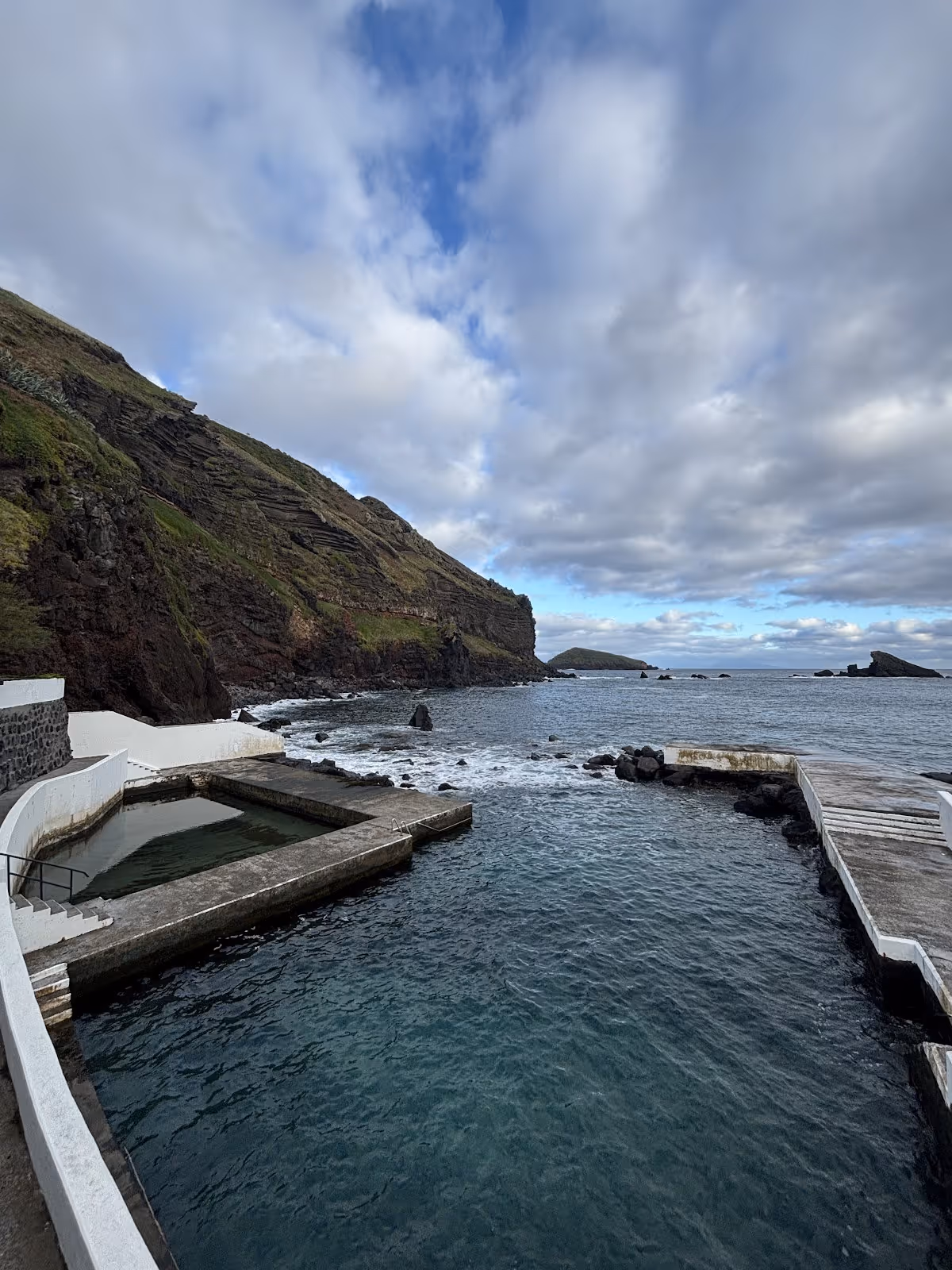 Outdoor T-shaped spa pool connected to the ocean at Termas do Carapacho with rocky cliffs by Santa Cruz da Graciosa Portugal.