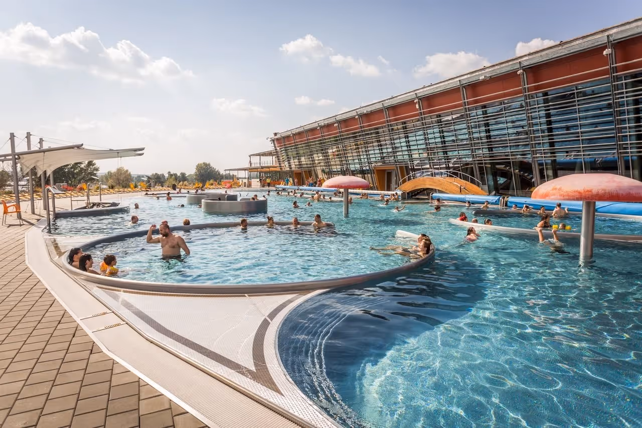 Outdoor hot spring soaking pools with round mushroom water fountains at Aqualand Moravia near Pasohlavky Czechia under a clear sky.