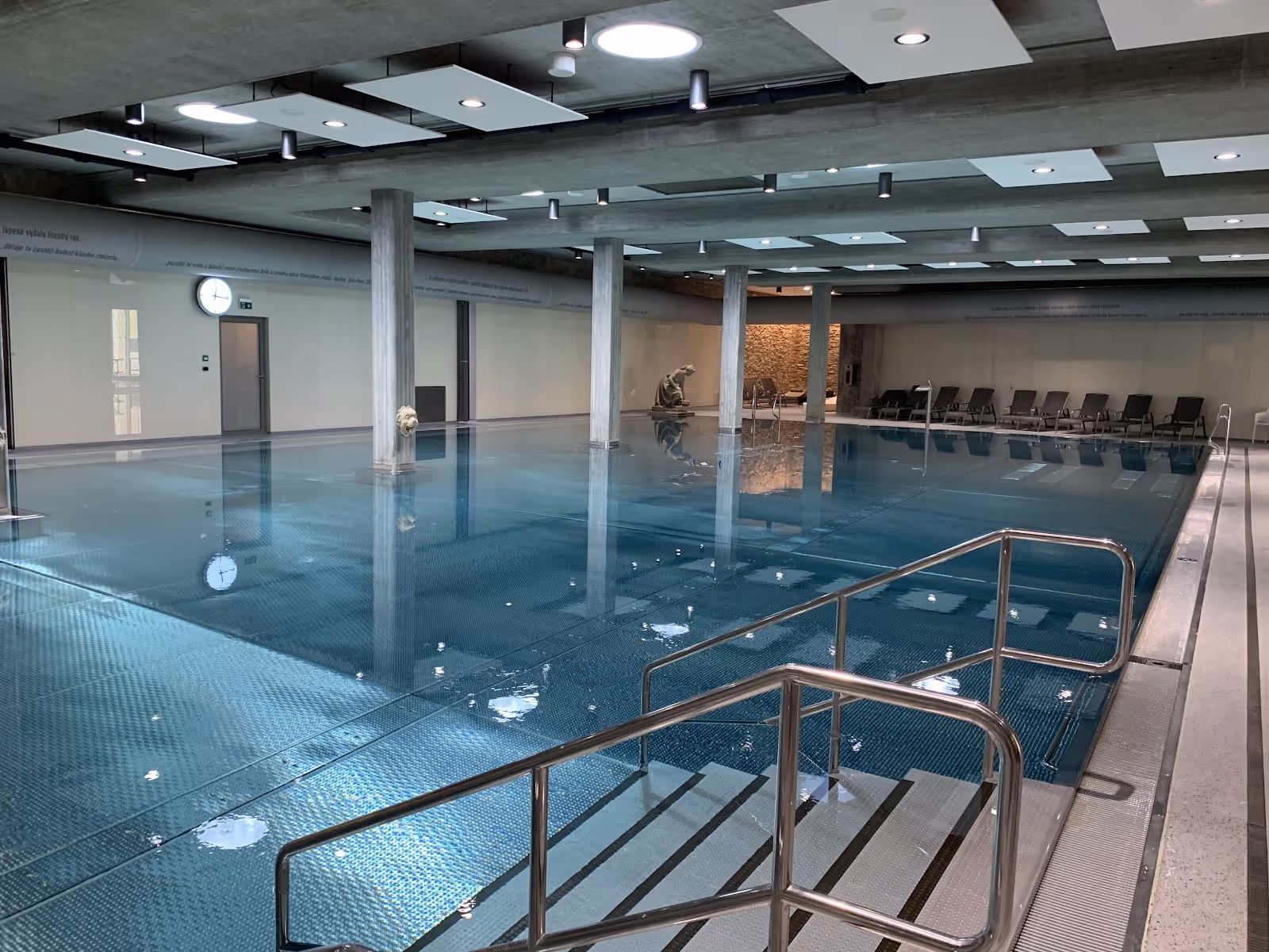 large indoor hot spring pool with blue tiled floor and metal handrails at imperial spa house in teplice czechia.
