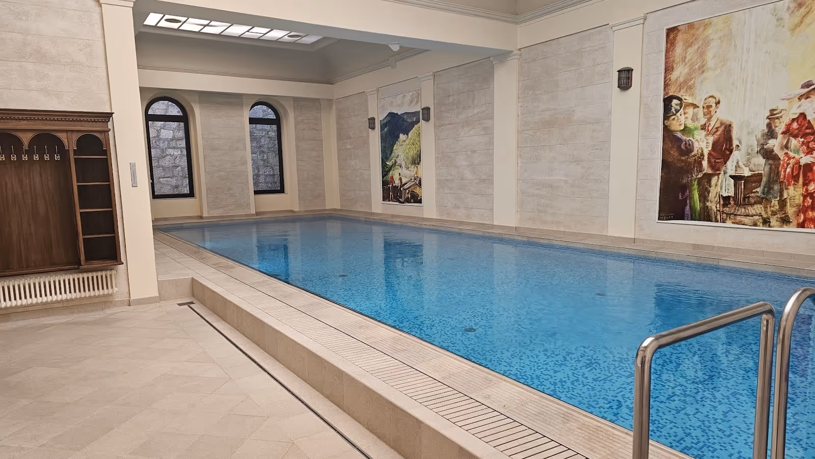 Indoor spa pool at Windsor SPA Hotel in Karlovy Vary Czechia with blue mosaic tiles and vintage paintings on walls.