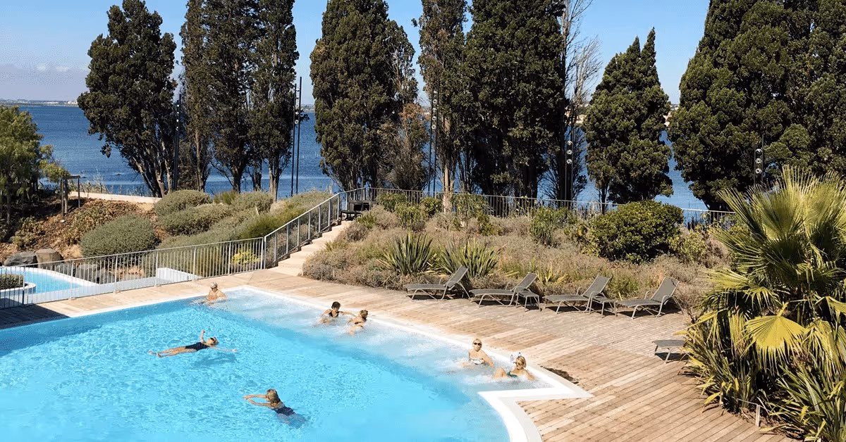 Outdoor hot spring pool at La Parenthese Obalia with people soaking and a lake view near Sete, France.