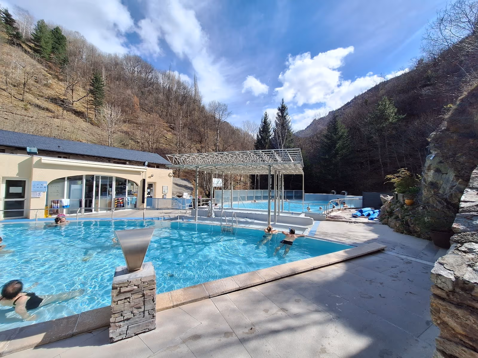 Outdoor spa pools with clear water and a small waterfall feature at Les Bains de Saint-Thomas near Fontpédrouse, France.