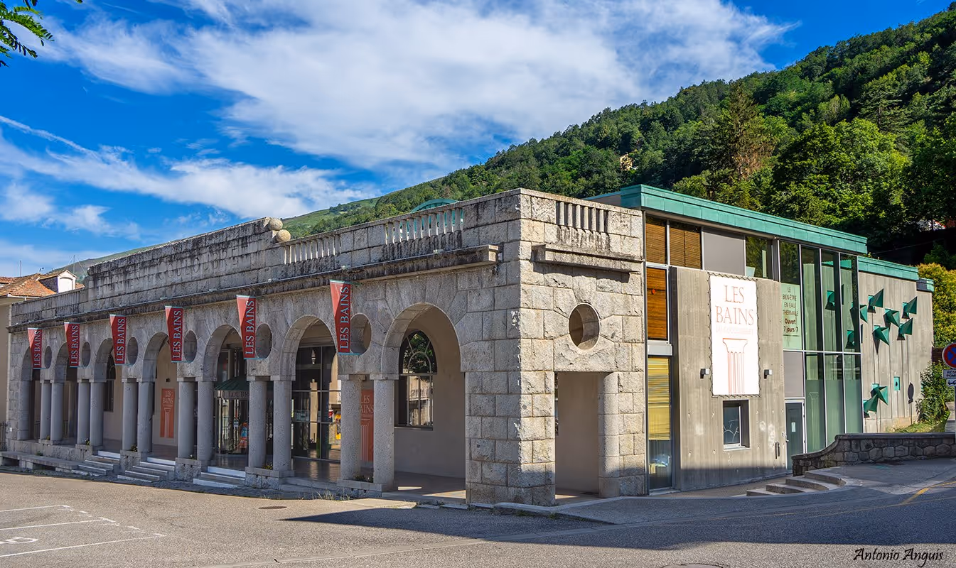 Modern stone and glass exterior of Les Bains du Couloubret hot spring facility with greenery in the background near Ax-les-Thermes France.