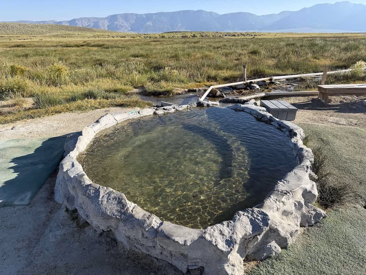 Hilltop Hot Springs, California - stone-and-cement soaking tub on elevated plateau with 360-degree Sierra Nevada views near Mammoth Lakes