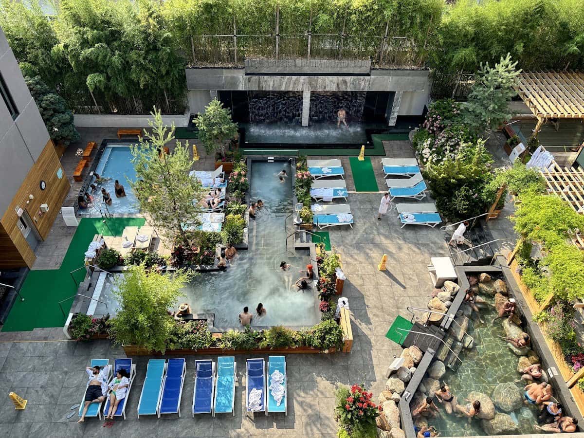 Bird's eye view of people soaking in multiple outdoor pools and sunbathing in Sojo Spa Club New Jersey