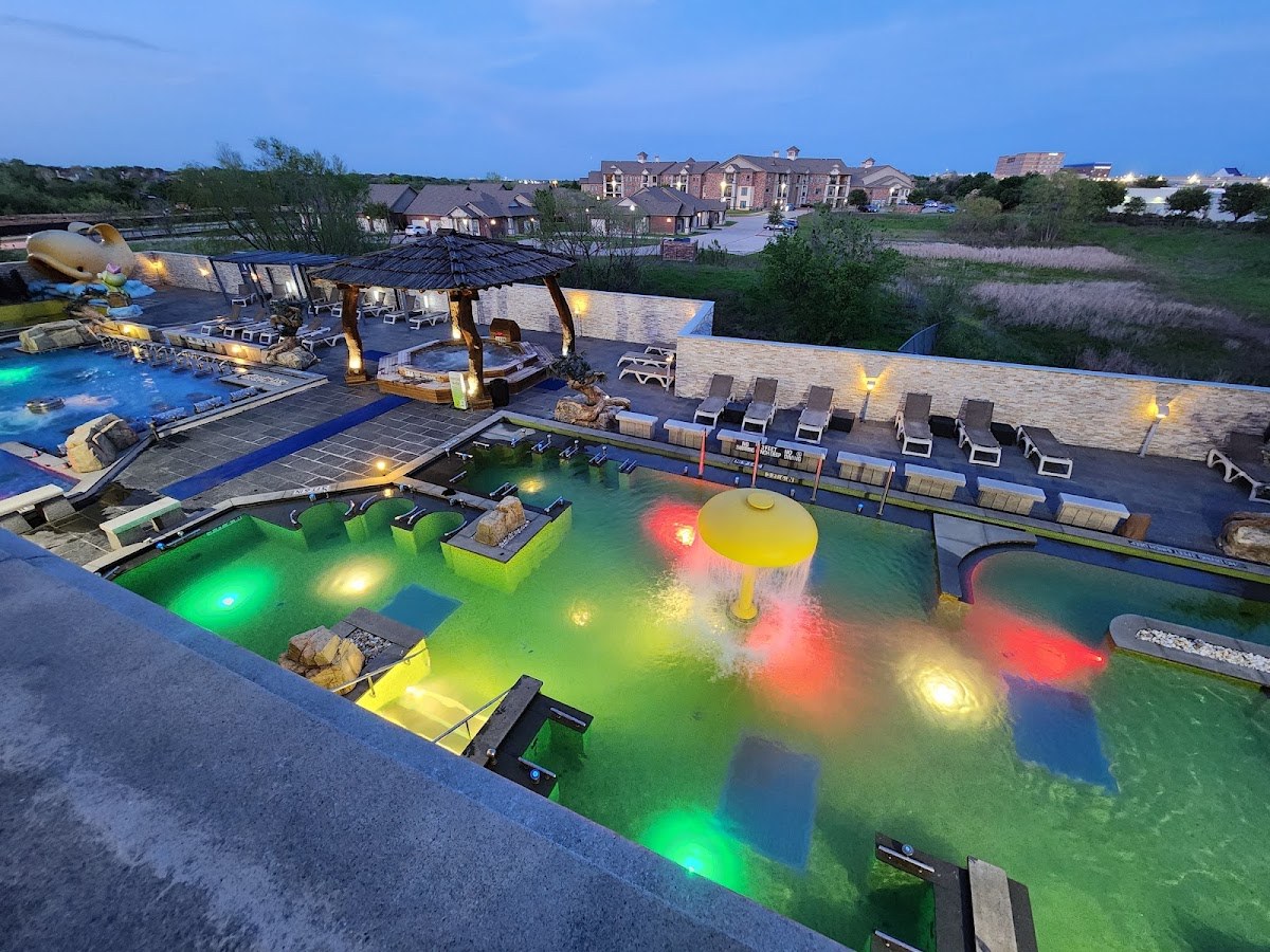 Outdoor heated pool area with colourful evening lights at Spa Castle Texas