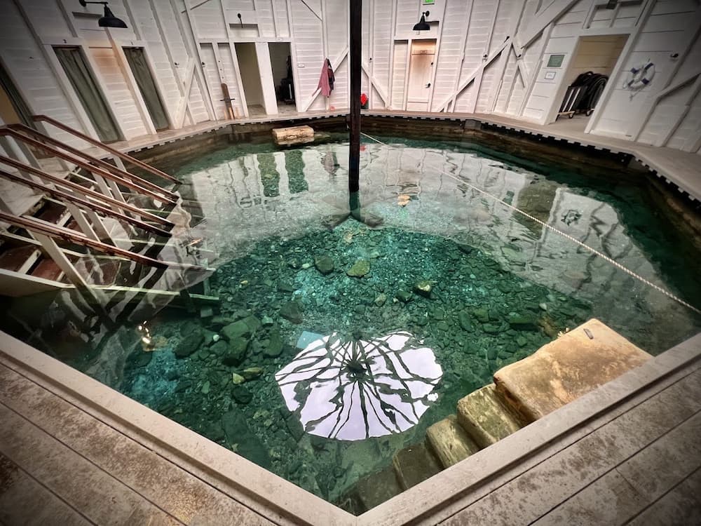 octagonal wooden bathhouse enclosing an emerald green mineral soaking pool at warm springs pools virginia