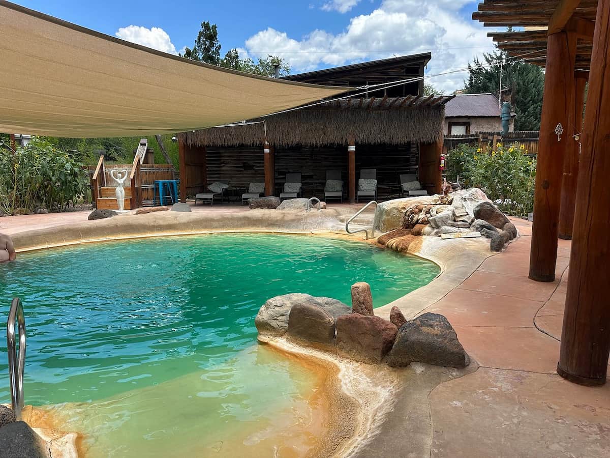 Outdoor shaded hot green hot spring pool with mountain backdrop in jemez hot springs new mexico