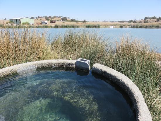 Concrete hot spring tub in front of a lake at franklin hot springs california