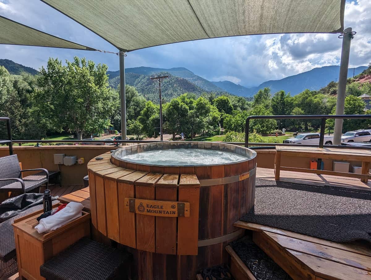 Outdoor shaded wooden hot spring tub with mountain valley views at sunwater spa hot springs colorado 