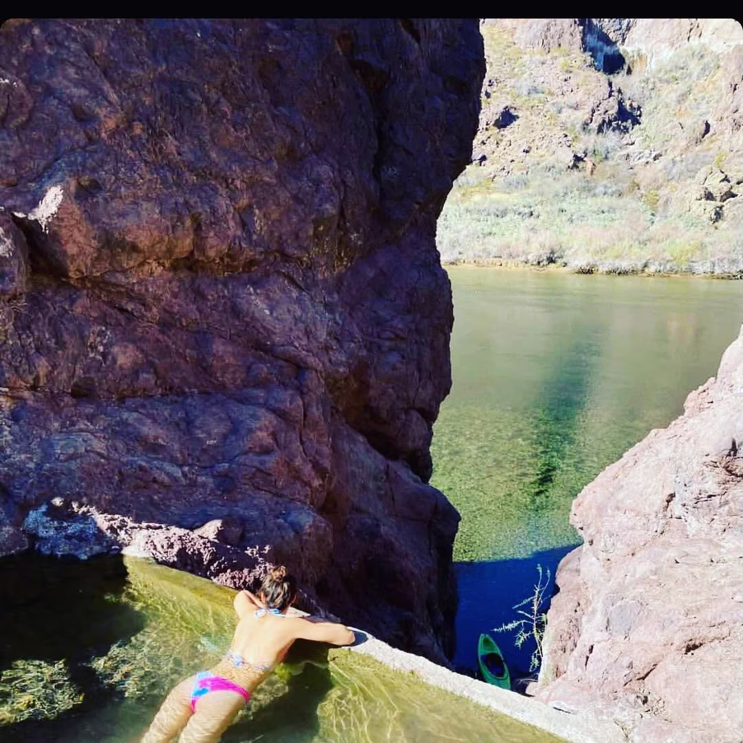 Woman soaking in outdoor hot spring pool above the colorado river in lone palm hot springs arizona