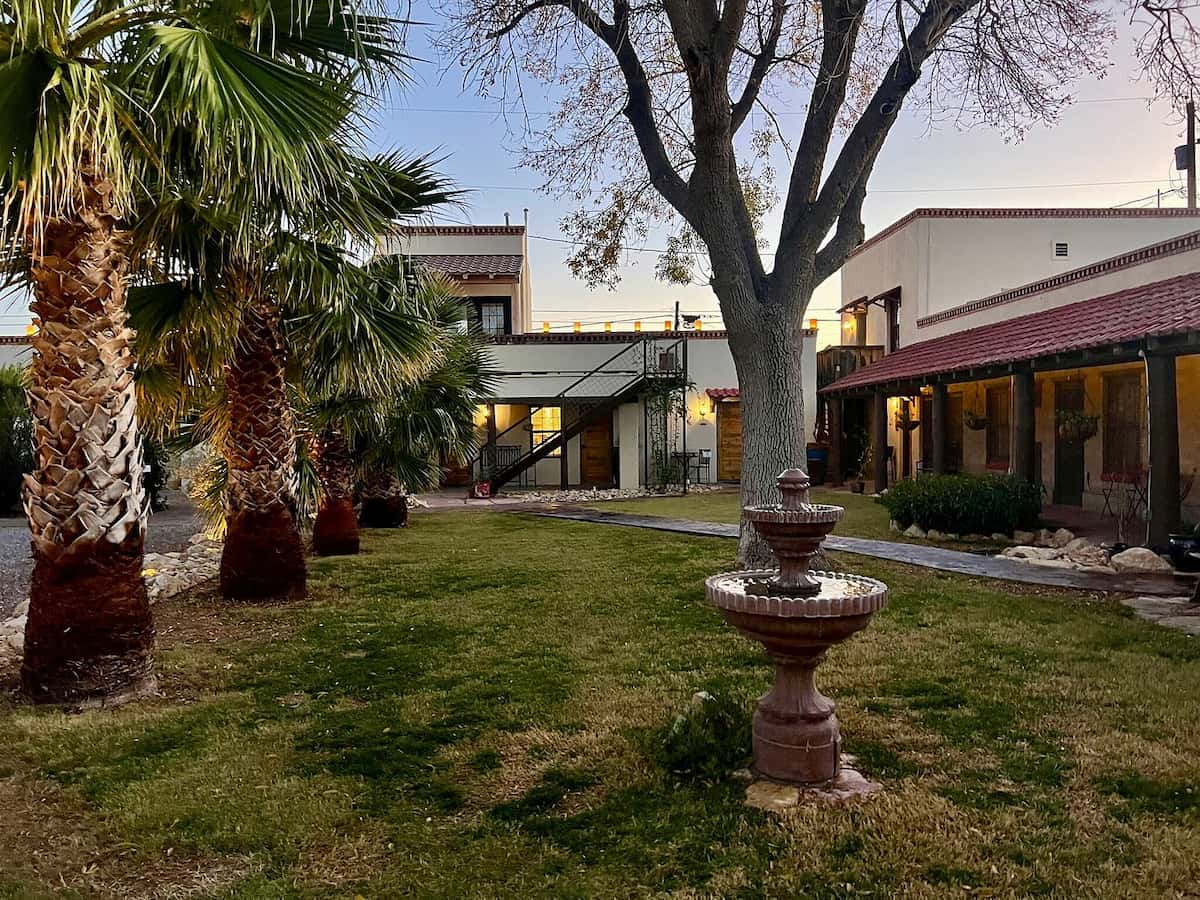 Garden with a fountain and palms with a hot springs house in the background at hoosier hot springs and inn new mexico