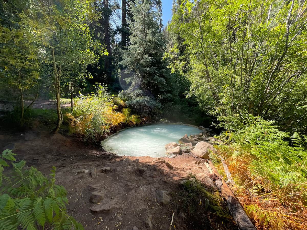 turquoise geothermal pool in a forest clearing in autumn at geyser warm spring colorado