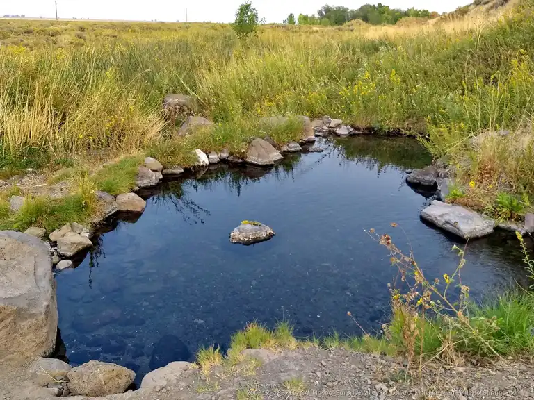 natural hot spring pool surrounded by a meadow at squaw baths eagleville hot springs california