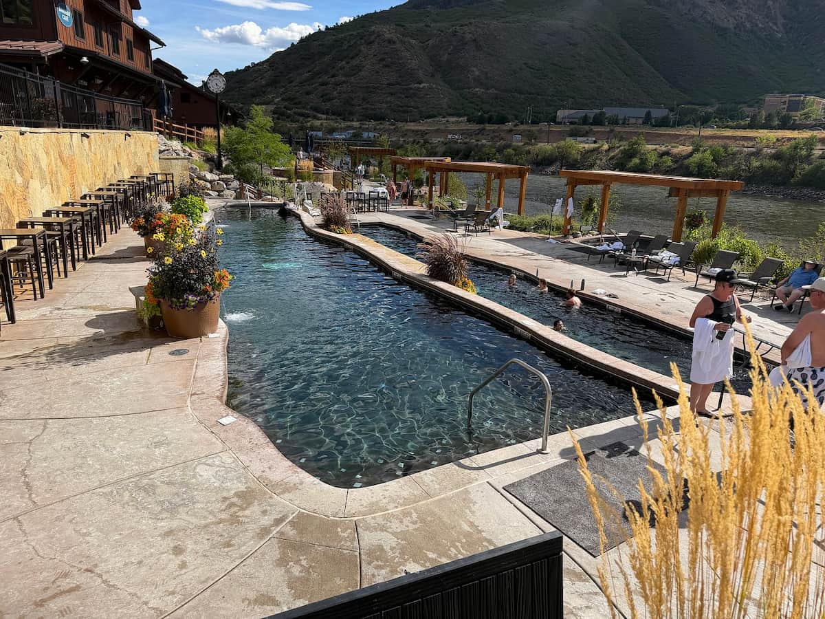 People soaking in outdoor developed hot spring pools above the colorado river at iron mountain hot springs colorado
