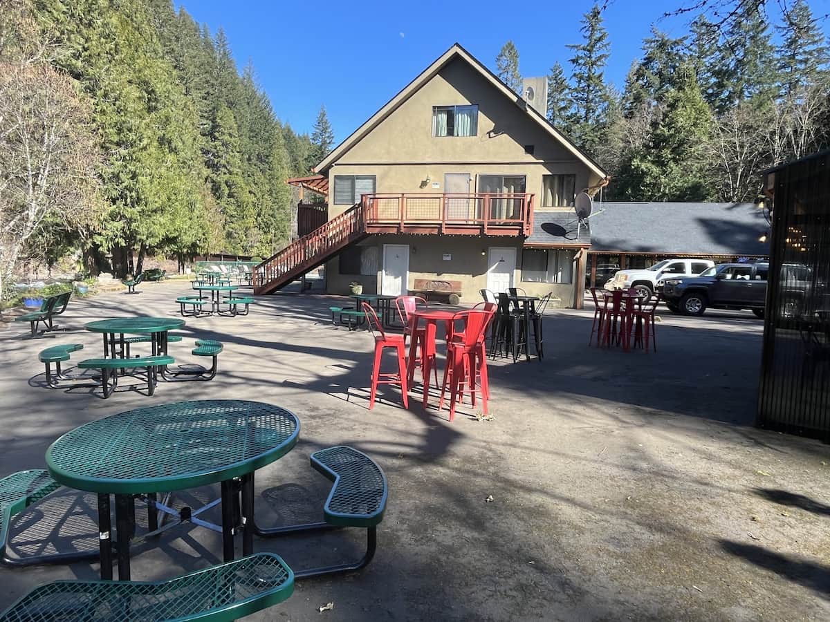 Outdoor area seating with resort in the background in a forest setting at belknap hot springs 