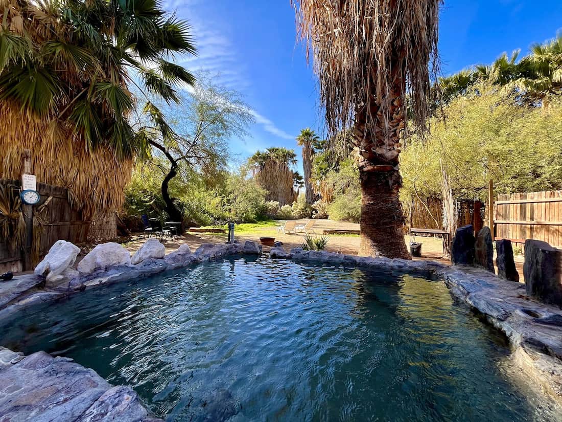 Outdoor hot spring tub with palms and desert views in the background at el dorado hot springs arizona