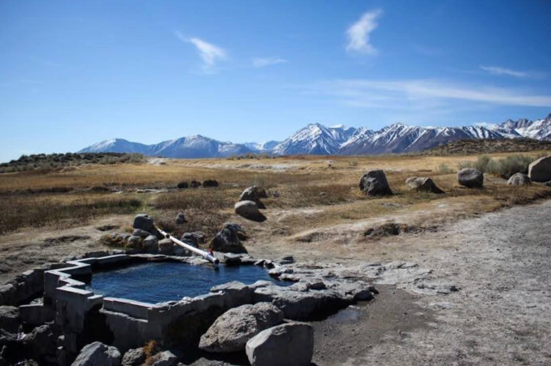 Outdoor rock lined hot spring pool with desert and mountain views at crab cooker hot springs california