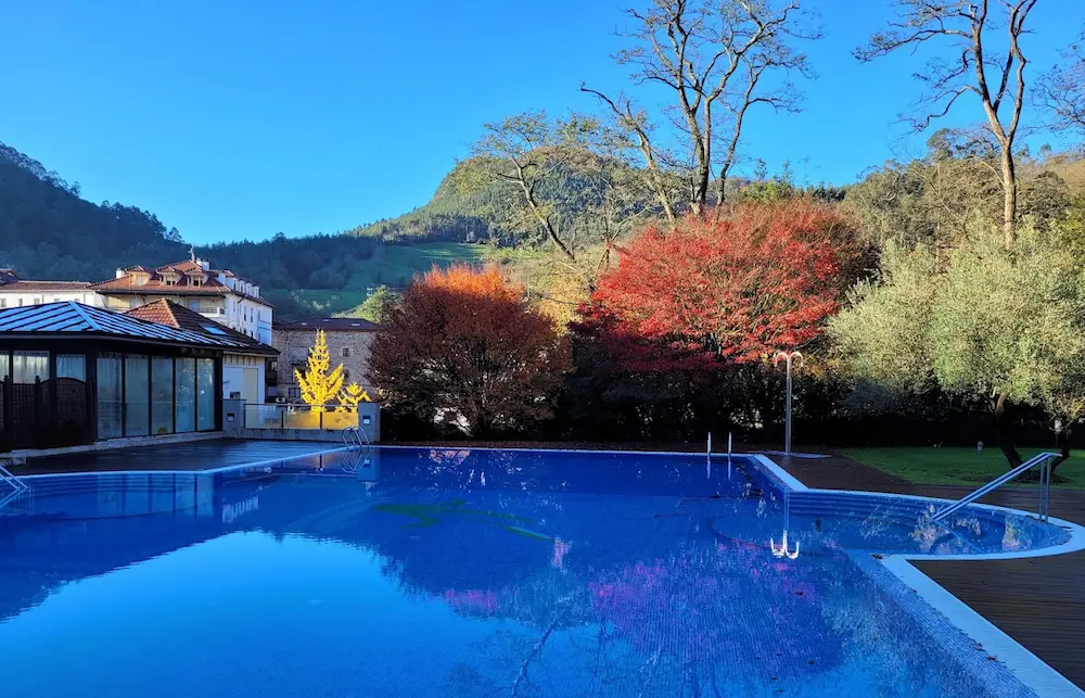 Outdoor hot spring pool in a developed resort surrounded by trees in autumn at balneario de puente viesgo in spain