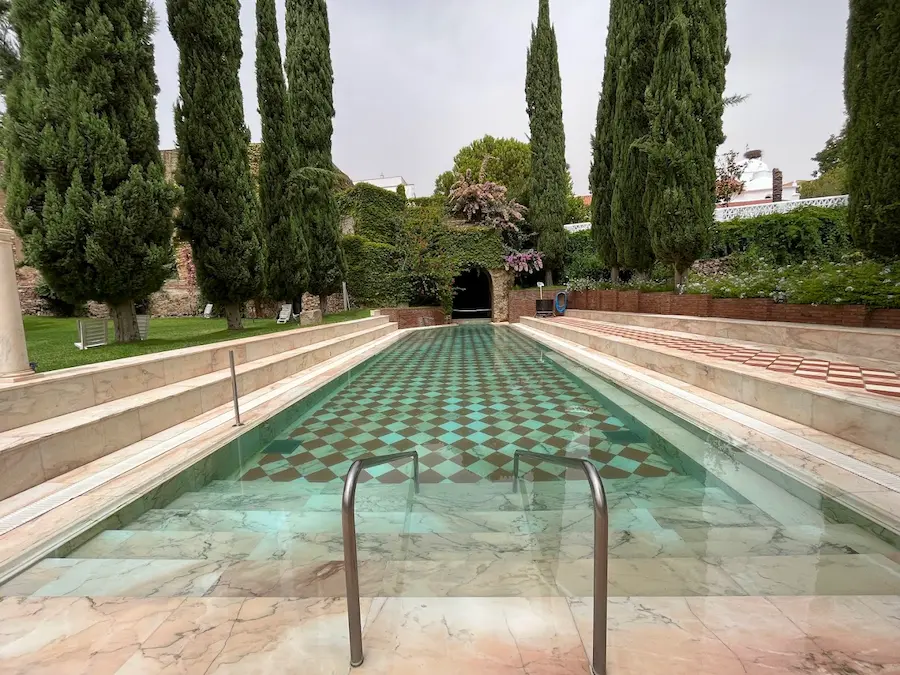 Outdoor hot spring pool surrounded by trees at balneario de alange in spain