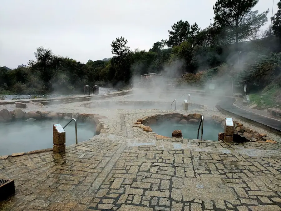 Steaming outdoor hot spring pools in a natural setting at termas do muino da veiga in spain