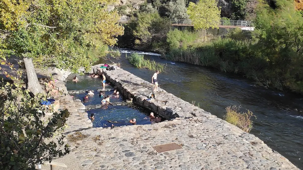 People soaking in outdoor concrete hot spring pools on the riverside at pozas de arnedillo in spain