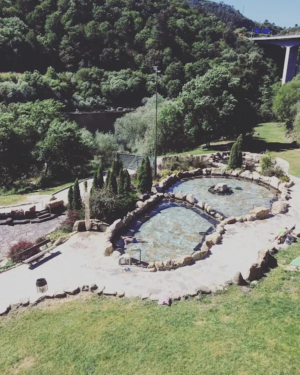 Outdoor rock lined and developed hot spring pools surrounded by river valley at termas de outariz in spain