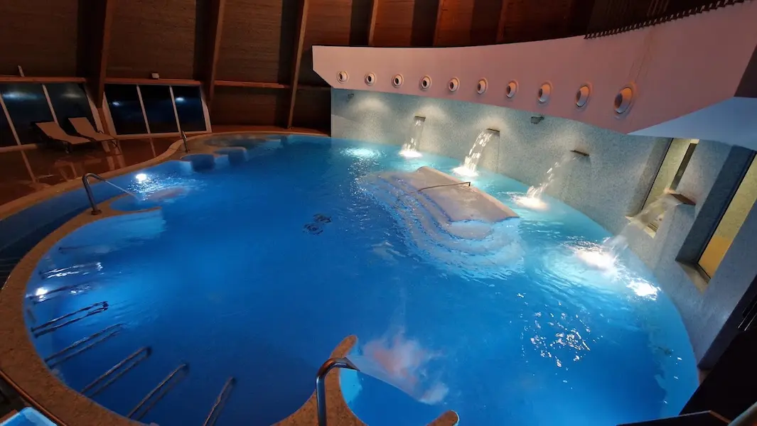 Indoor lit hot spring pool with massage streams in spa complex at termas do cro in portugal