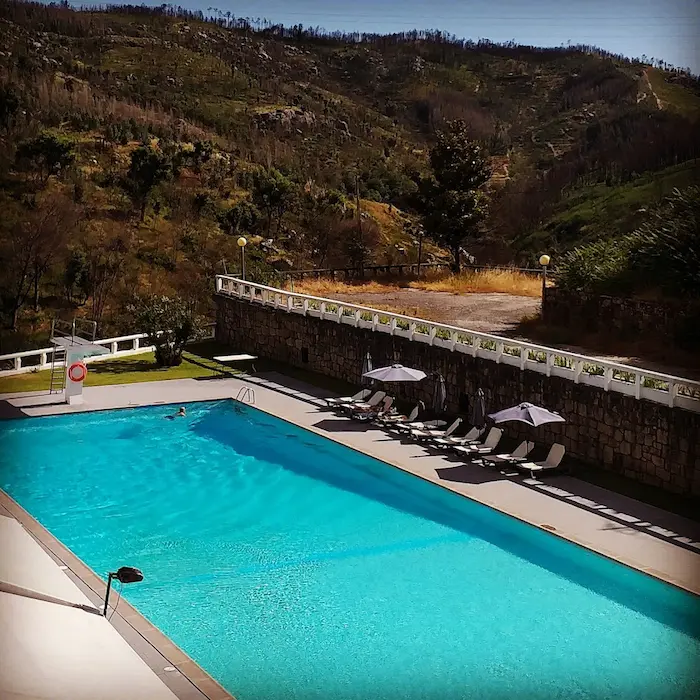 Outdoor hot spring pool in a resort with hills in the background at termas de felgueira in portugal