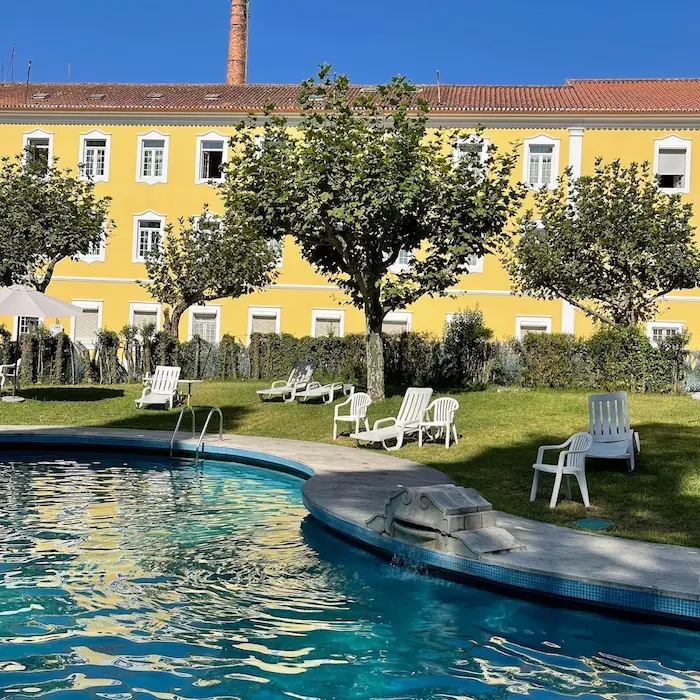Outdoor hot spring pool with resort in the background at termas da curia in portugal