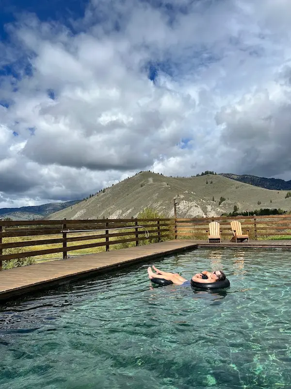 person soaking at a developed hot spring pool overlooking a valley and hills in the background at idaho rocky mountain ranch in idaho
