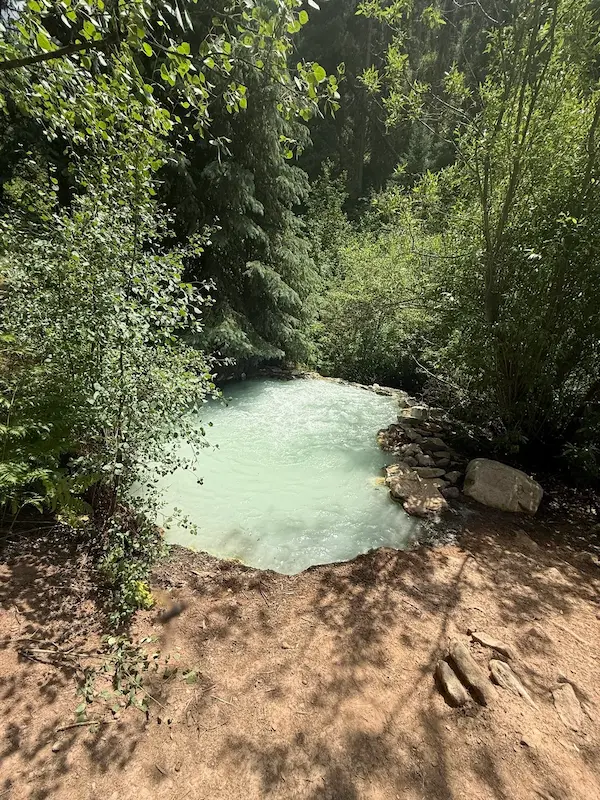 turquoise natural geothermal pool in a forest clearing at geyser warm spring in colorado