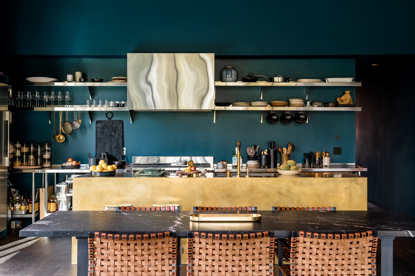 Kitchen with teal walls, a brass island and leather barstools