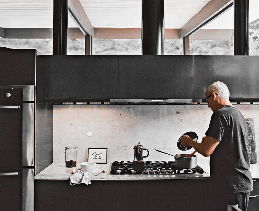Man cooking at a gas range in a dark modern kitchen