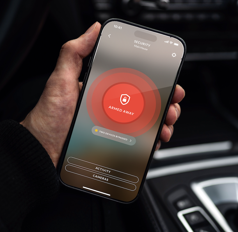 Hand holding a phone in a car, arming home security