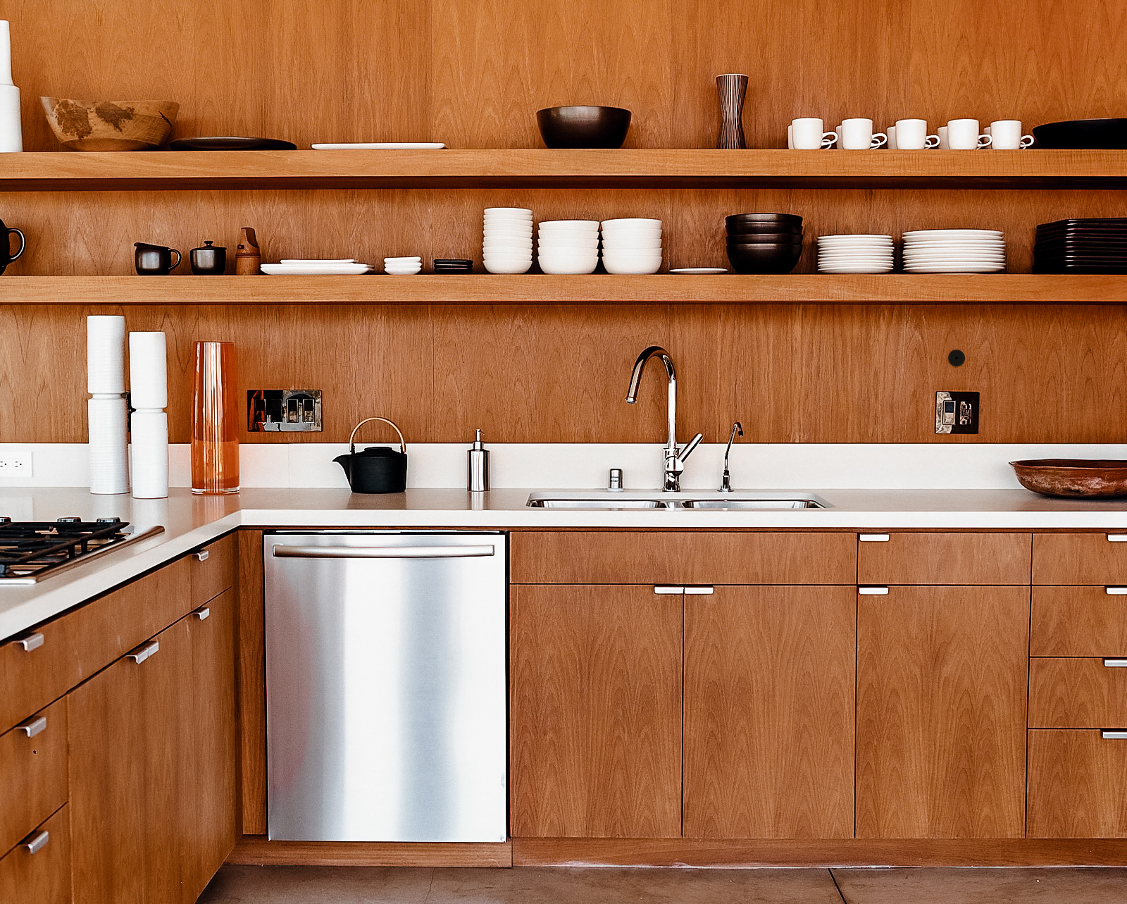 Warm wood kitchen with open shelving and a stainless dishwasher