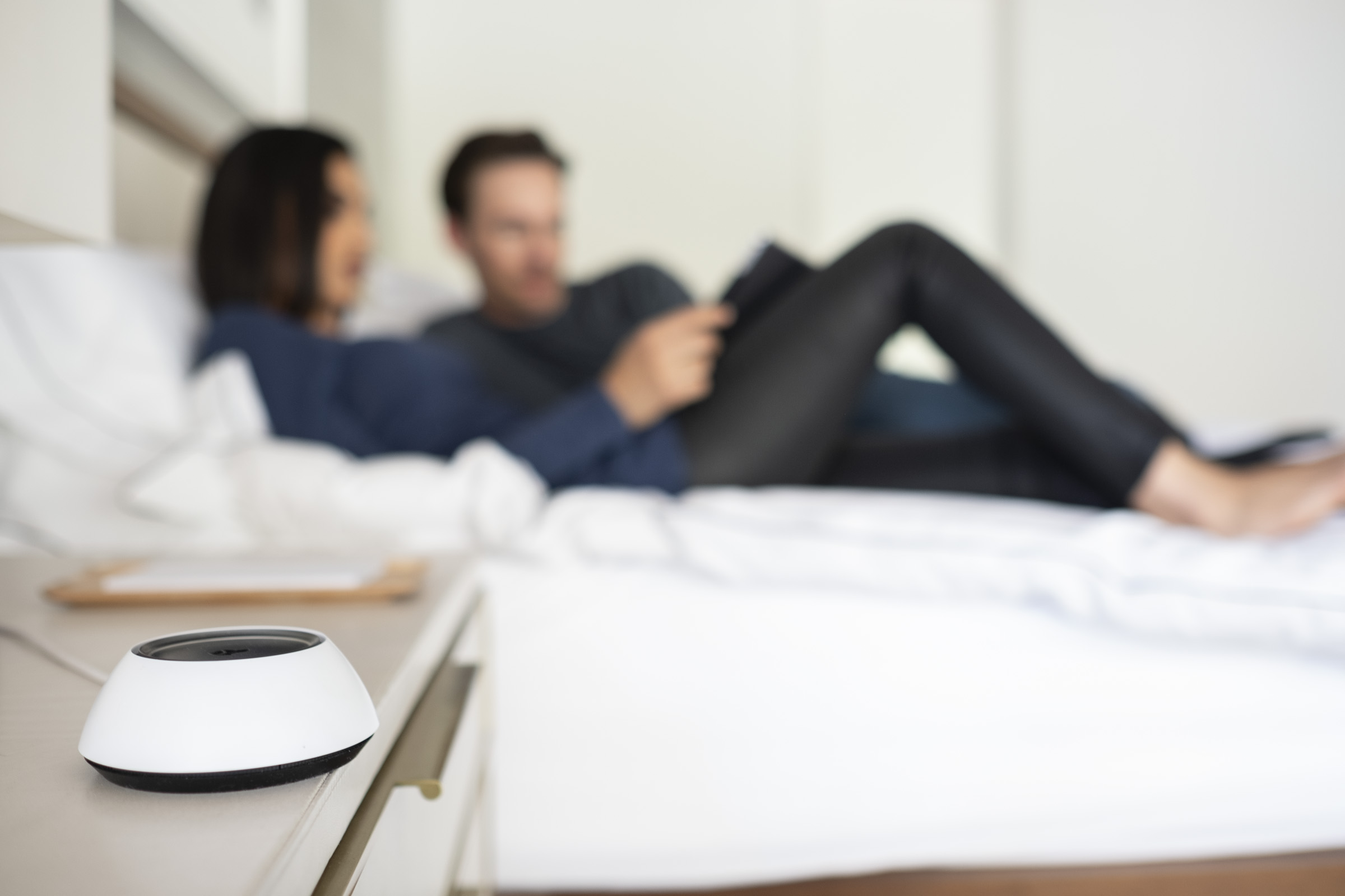 Josh Micro on a bedside table with a couple relaxing on the bed